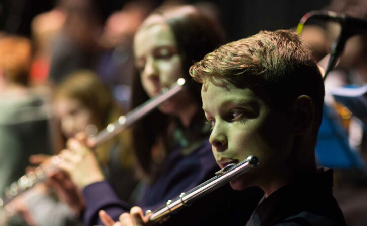 Close-up of a boy playing the flute in an orchestra