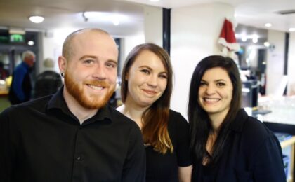 Three smiling staff members in the foyer of the theatre