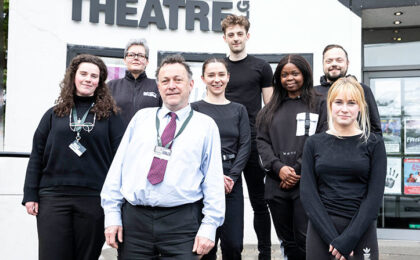 Eight Box Office staff members standing for a photo in front of the theatre