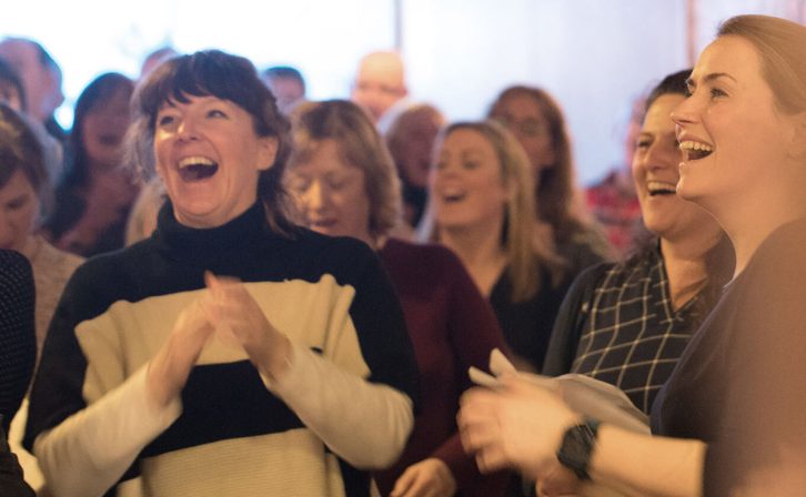A crowd of patrons laughing and clapping in the theatre's atrium A crowd of patrons laughing and clapping in the theatre's atrium