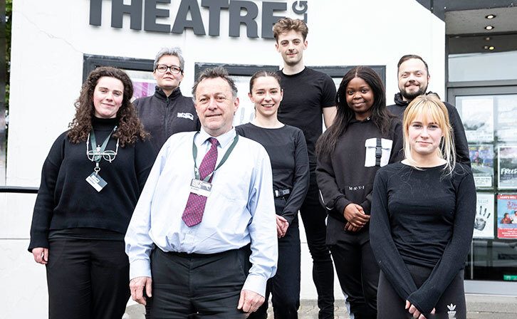 Eight Front of House staff members standing for a photo in front of the theatre