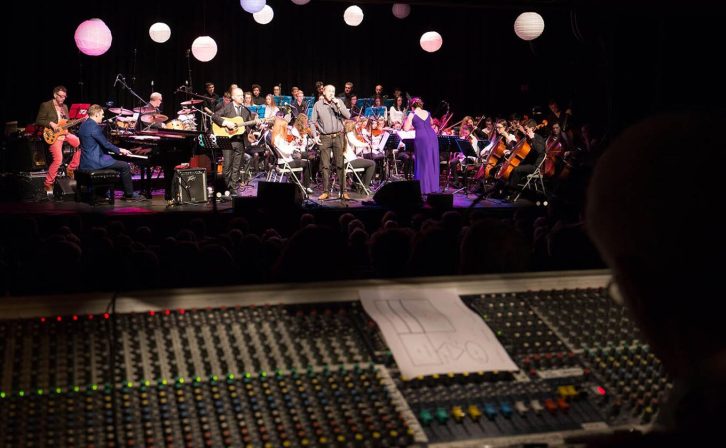 A band and orchestra performing on the theatre's stage A band and orchestra performing on the theatre's stage