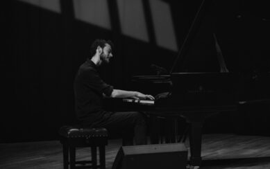 A black and white photo of Nils Kavanagh playing a piano.