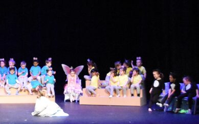 A photo of three groups of preschool children on a theatre stage. 