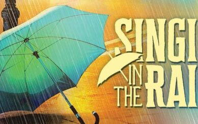 The poster for the musical Singin' in the Rain. On the left is n open blue umbrella, on the right the title of the show in large yellow lettering.