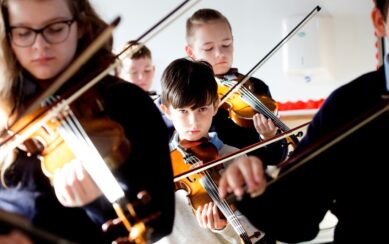 A photograph of a group of young violin players
