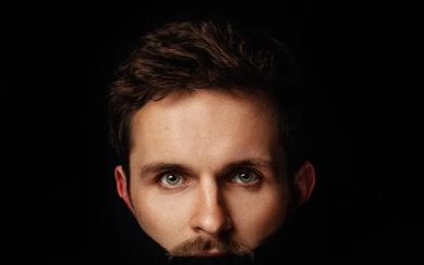 Image of comedian Vittorio Angelone's face against a back background with is mouth blacked out 