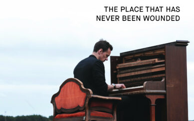 Artist Niall Breslin sitting at a piano in a rural landscape 