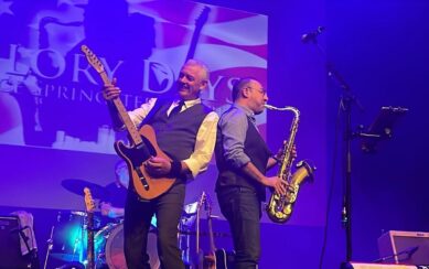 Man playing a guitar next to a man playing a saxophone 