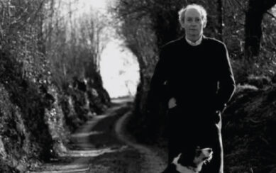 Man standing next to a dog on a forest road 