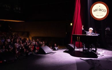 Pianist on stage under spotlight waving at audience
