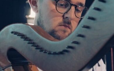 Man in glasses playing the harp 