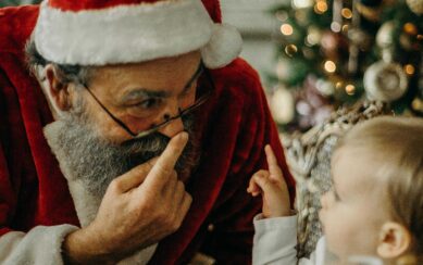 Santa Clause touching his nose and a baby pointing at him