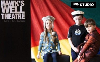 Kids in front of a colourful flag