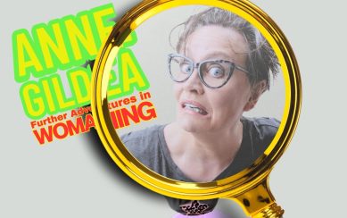 Artist Anne Gildea making a funny face under a massive magnifying glass 