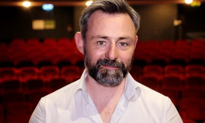 A portrait photo of Kieran Griffiths with theatre seats in the background