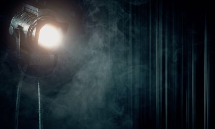 A photograph of a spotlight, stage curtain, and haze. A photograph of a spotlight, stage curtain, and haze.