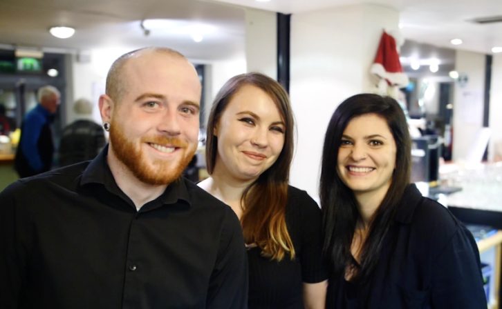 Three smiling staff members in the foyer of the theatre Three smiling staff members in the foyer of the theatre