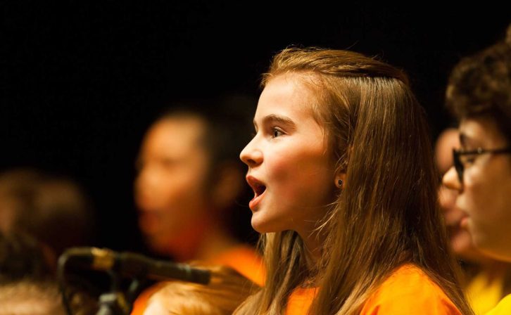 Close-up of a girl singing with choir on the main stage of the theatre