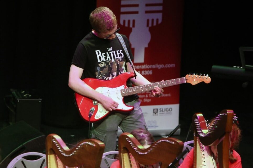A young performer with an electric guitar on stage