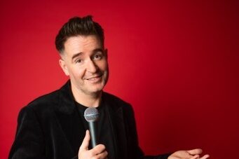 A photograph of Jarlath Regan against a red backdrop