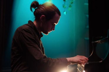 A profile photograph of Fergus McCreadie playing piano