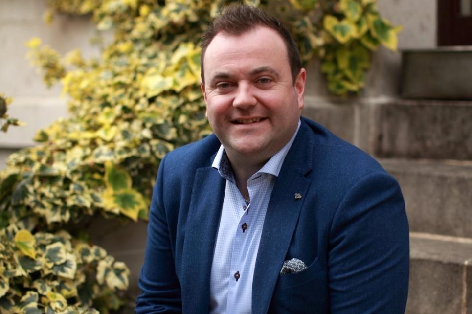 Singer Patrick Feeney sitting on some steps smiling for the camera Singer Patrick Feeney sitting on some steps smiling for the camera
