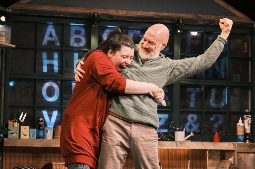 A man and a woman celebrating, her hugging him and him punching the air