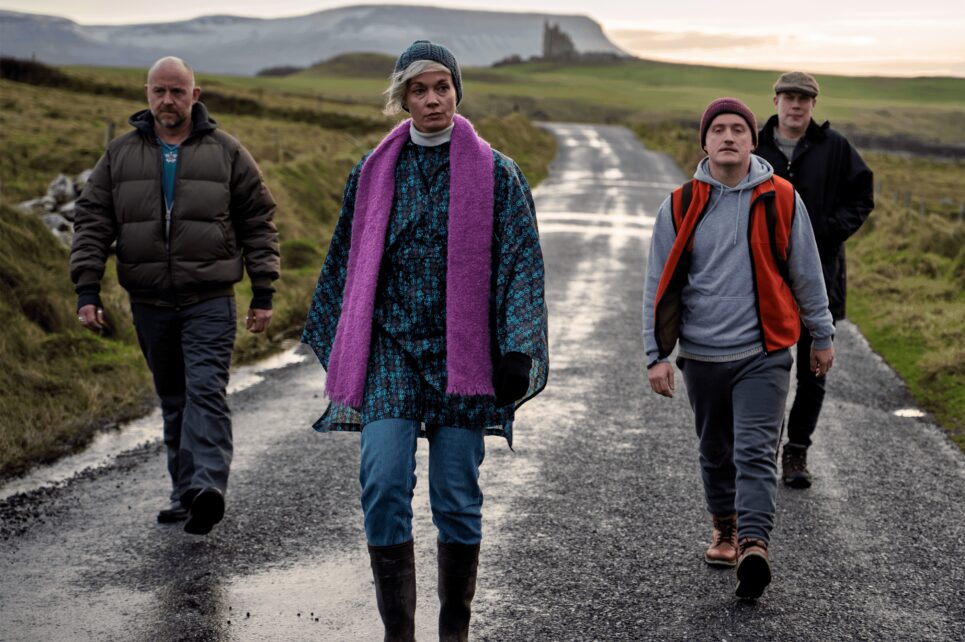 One woman walks ahead while three men follow down an empty road One woman walks ahead while three men follow down an empty road