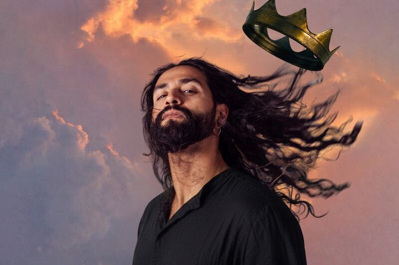 man with long hair blowing in the wind and his crown blowing away 