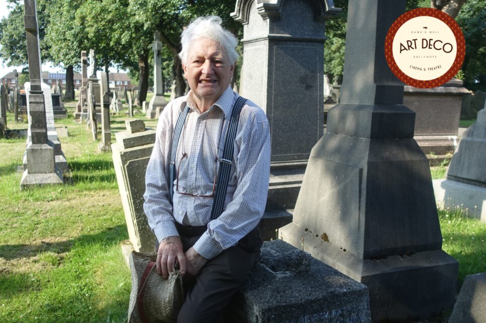 Man sitting on a gravestone in a graveyard
