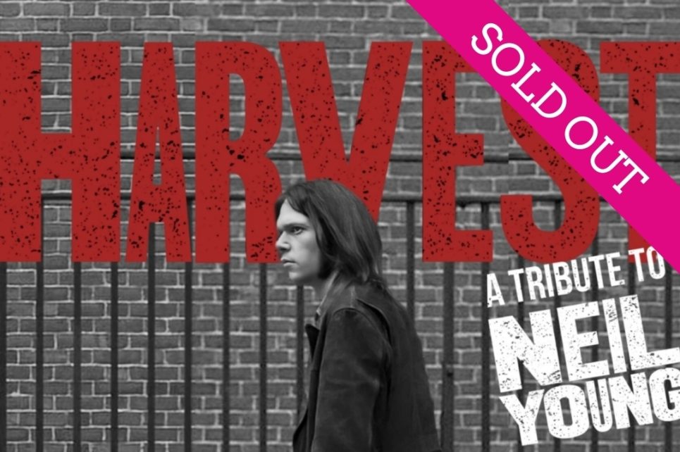 A photograph of Neil Young walking past a brick wall. On the wall is the word Harvest and the text A Tribute to Neil Young