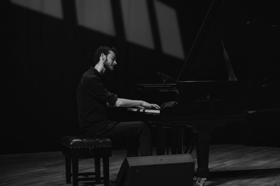 A black and white photo of Nils Kavanagh playing a piano.