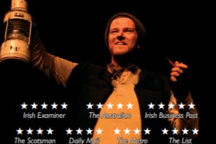 The poster for the event "Tom Crean: Antarctic Explorer". It shows Tom Crean on stage, holding up a metal lantern in his left hand.