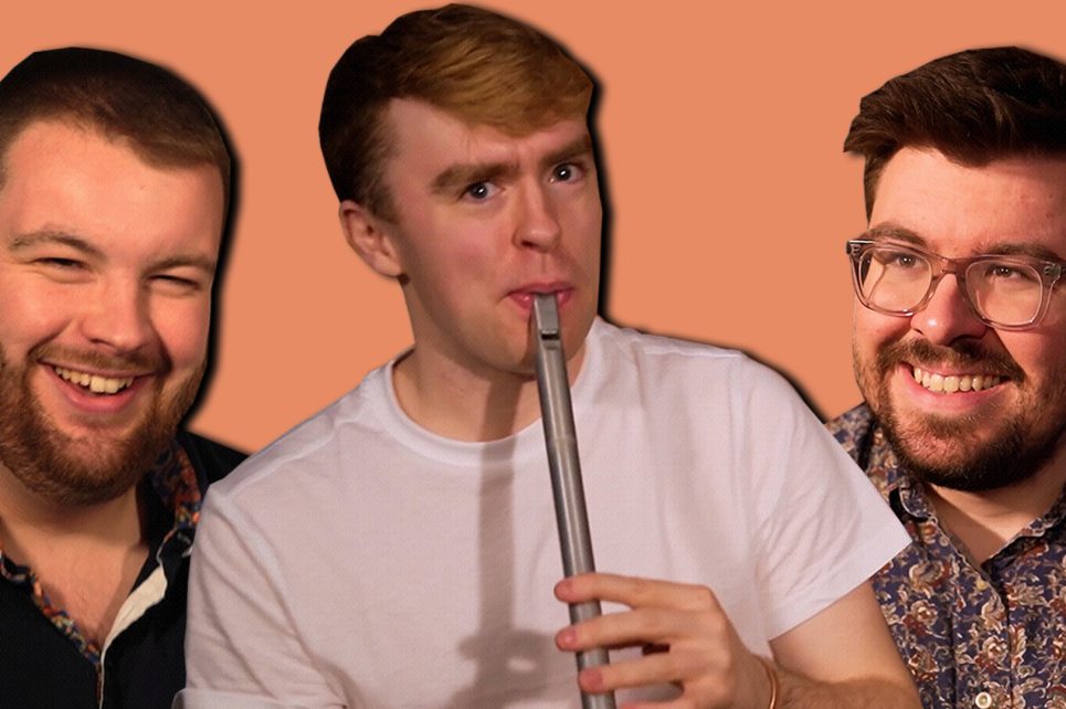 One man with a flute flanked by two other smiling men. One man with a flute flanked by two other smiling men.