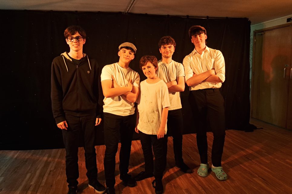 Five young boys posing together, smiling into the camera