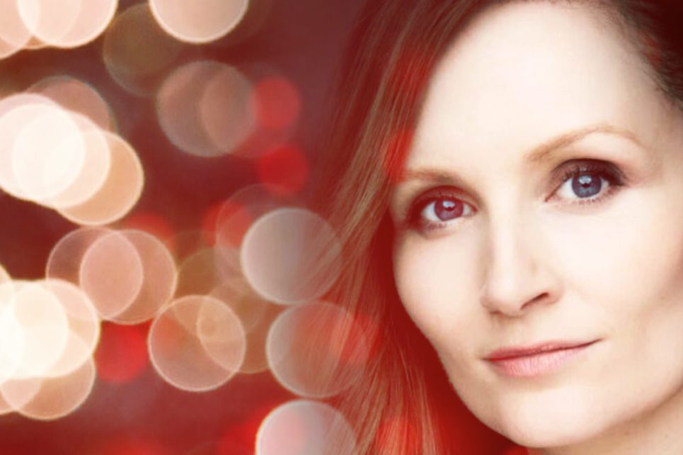 A stylized photograph of Nichola MacEvilly with blurred Christmas lights in the background. A stylized photograph of Nichola MacEvilly with blurred Christmas lights in the background.