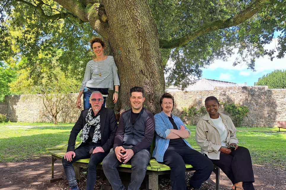 Artists from A Week At The Well posing below a tree