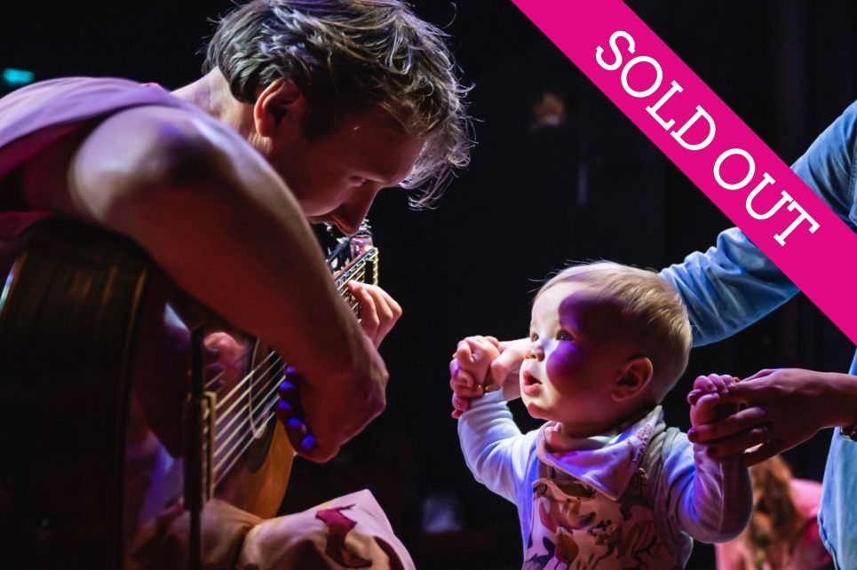 A musician is playing guitar for a baby