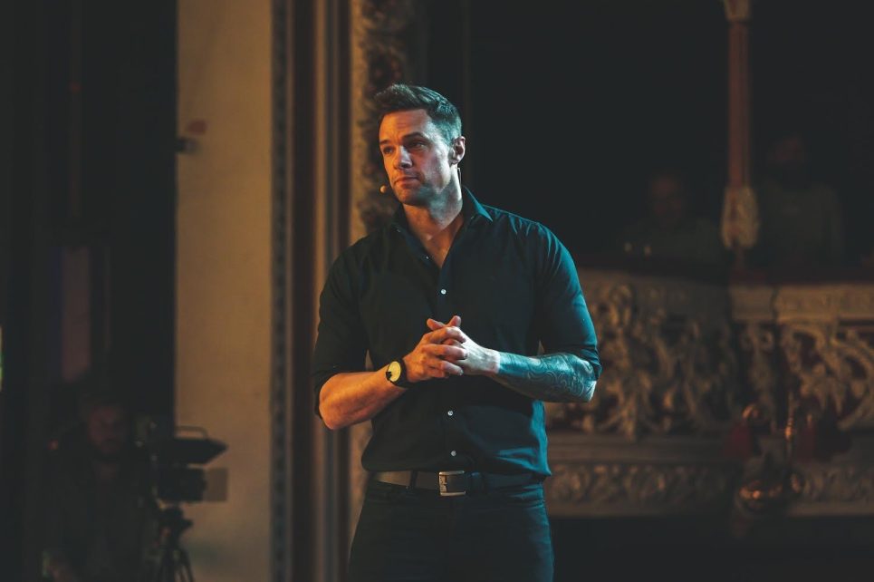 A photograph of Niall Breslin standing on stage.
