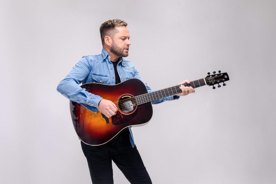 A photo of Derek Ryan holding a guitar
