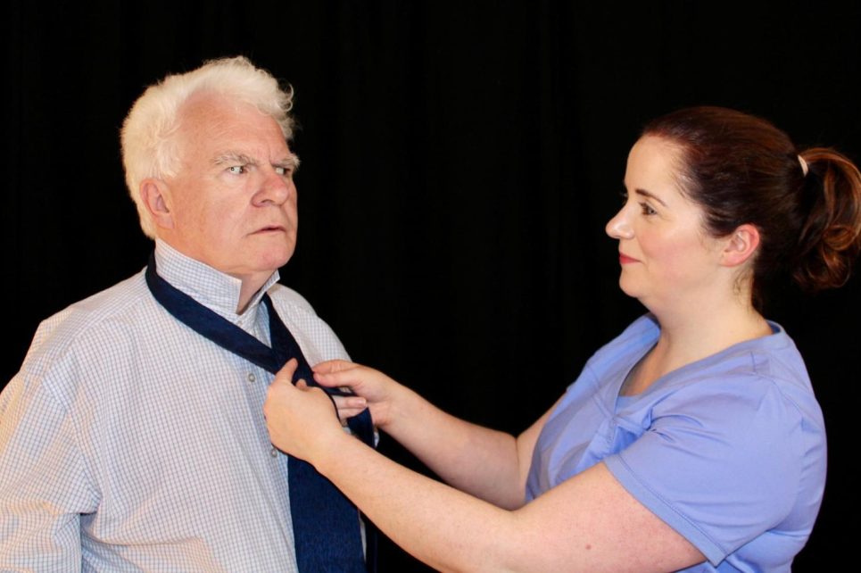 A nurse ties a tie for a puzzled inspector. A nurse ties a tie for a puzzled inspector.