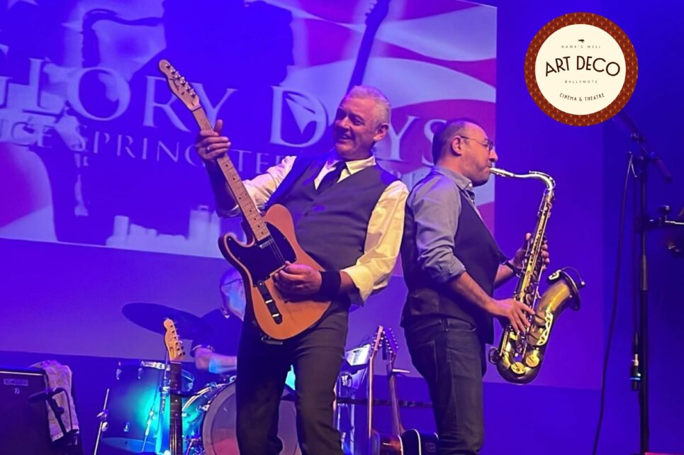 A band performs on a purple-lit stage in front of a "Glory Days" backdrop. A guitarist and a saxophonist stand back-to-back in the foreground.
