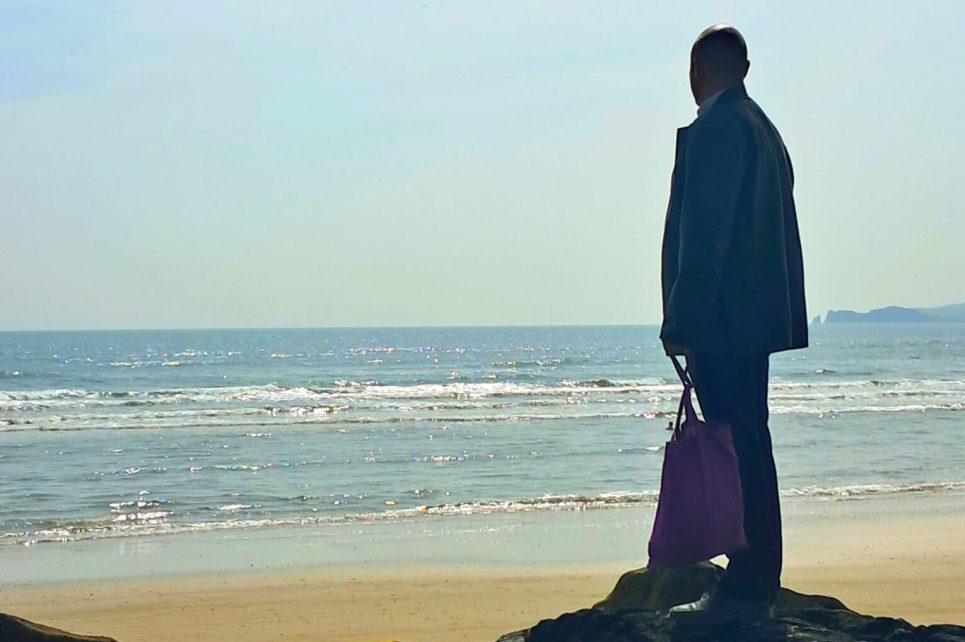 Silhouette of a man standing on some rocks staring out at the sea Silhouette of a man standing on some rocks staring out at the sea