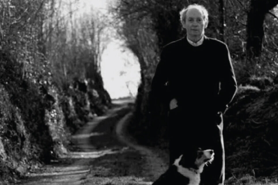 Man standing next to a dog on a forest road
