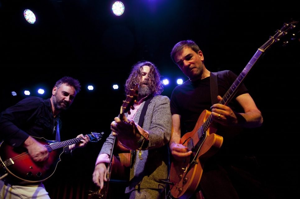 A photograph of the musicians from the Hothouse Flowers as they perform on stage. A photograph of the musicians from the Hothouse Flowers as they perform on stage.
