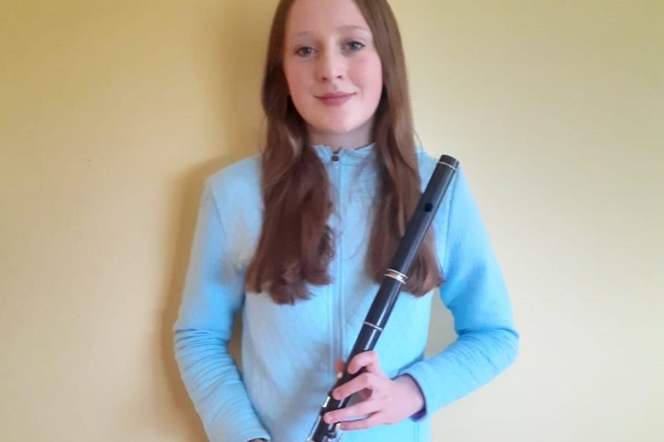 Young girl posing with her flute and smiling
