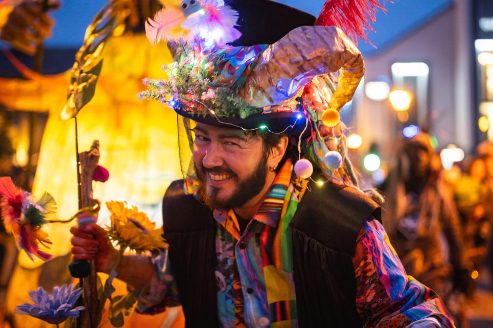 A man in a brightly colored suit is smiling while on parade.