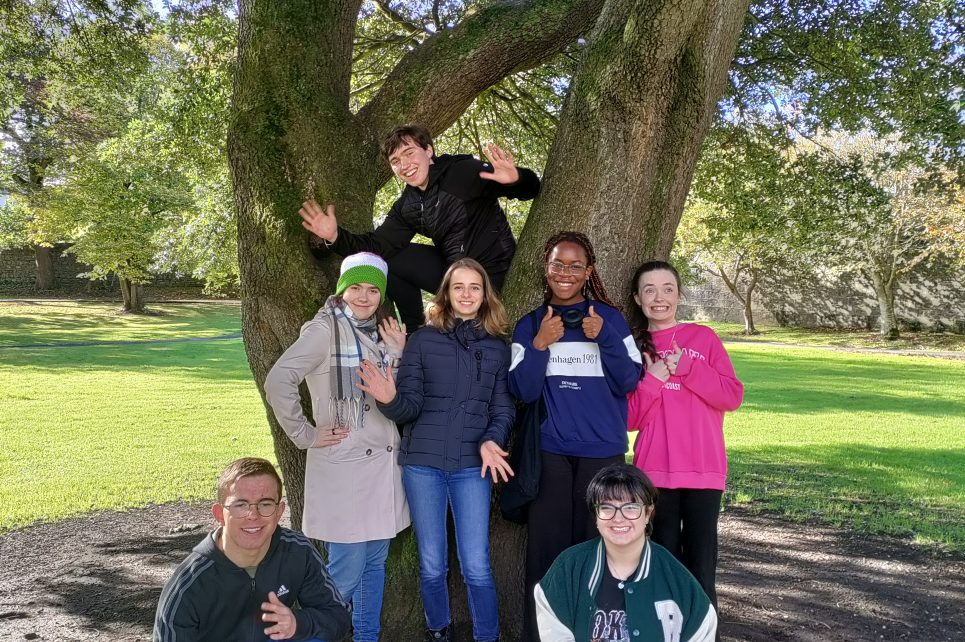 Children smiling for the camera against a tree in a park