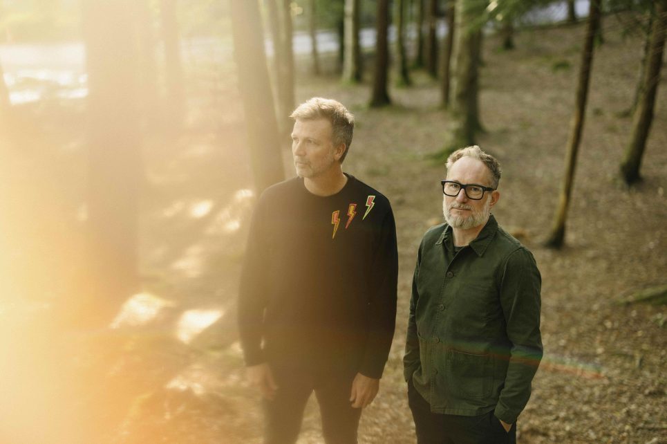 Paul Noonan & Brian Crosby standing in a forest Paul Noonan & Brian Crosby standing in a forest